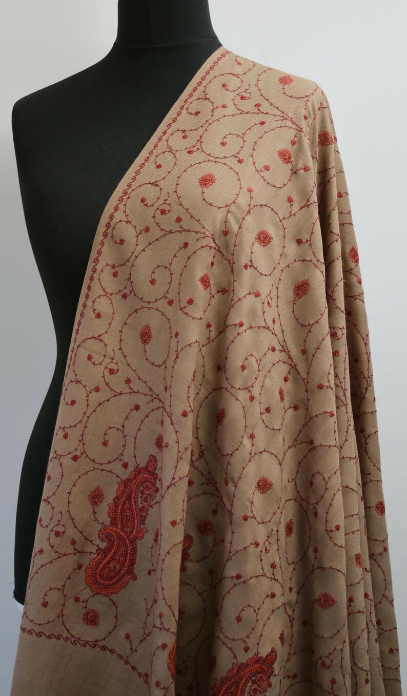 May include: A brown shawl with red embroidery featuring a paisley design and intricate floral patterns.