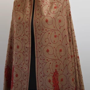 May include: A brown shawl with red embroidery in a paisley pattern. The shawl is made of wool and has a soft, luxurious feel.