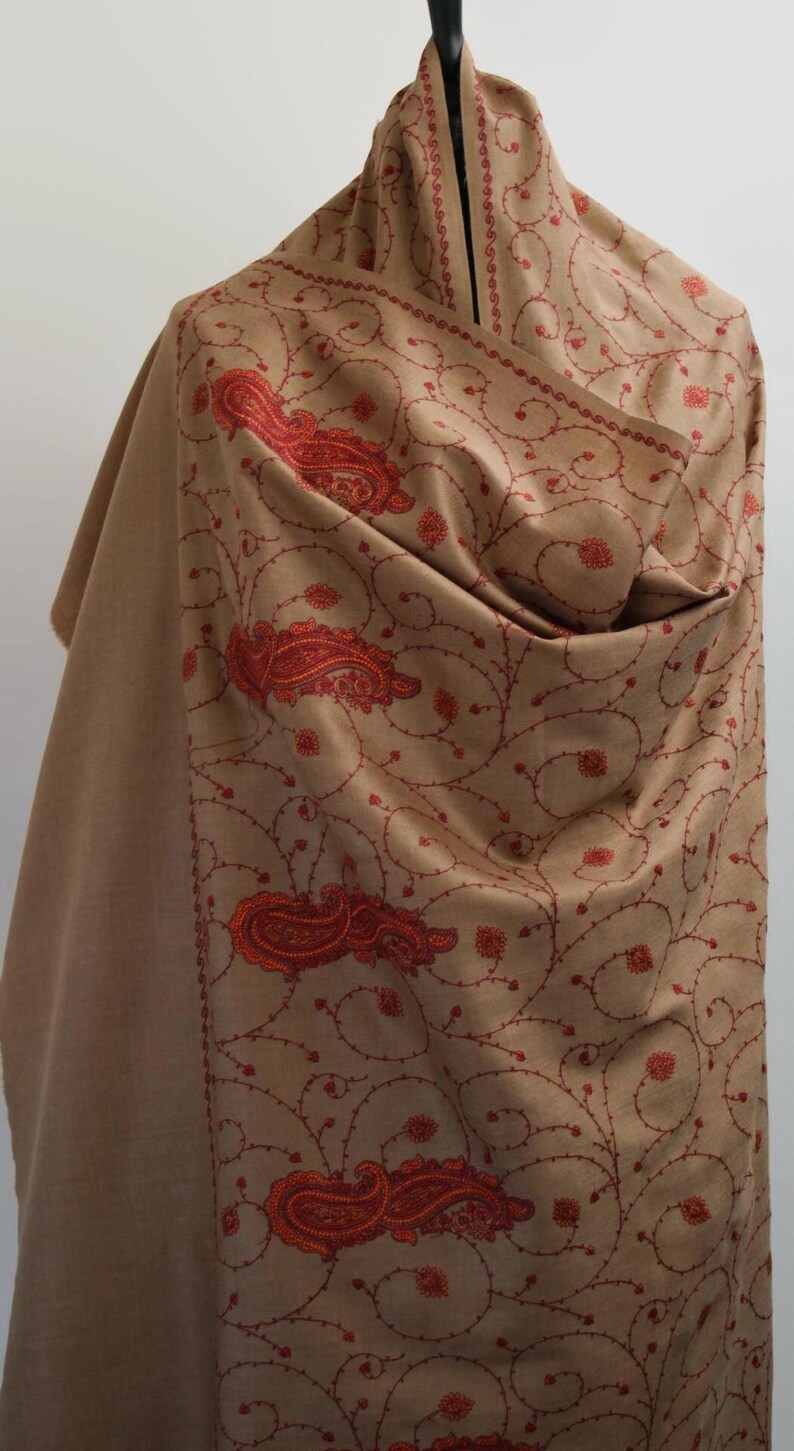 May include: A brown shawl with intricate red embroidery of paisley patterns and floral designs.