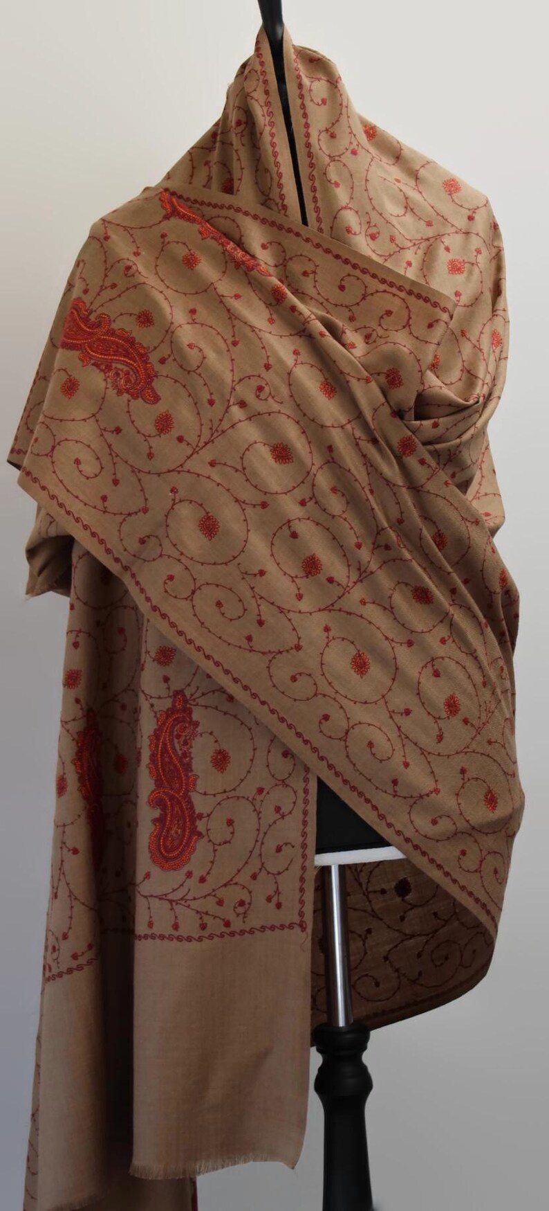 May include: A brown shawl with red embroidery featuring a paisley design and floral patterns.