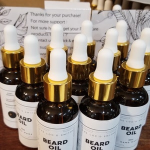 May include: Multiple bottles of beard oil with gold caps and white labels. The labels read "The Loc'd Smiths Beard Oil 30ml Hand Made".