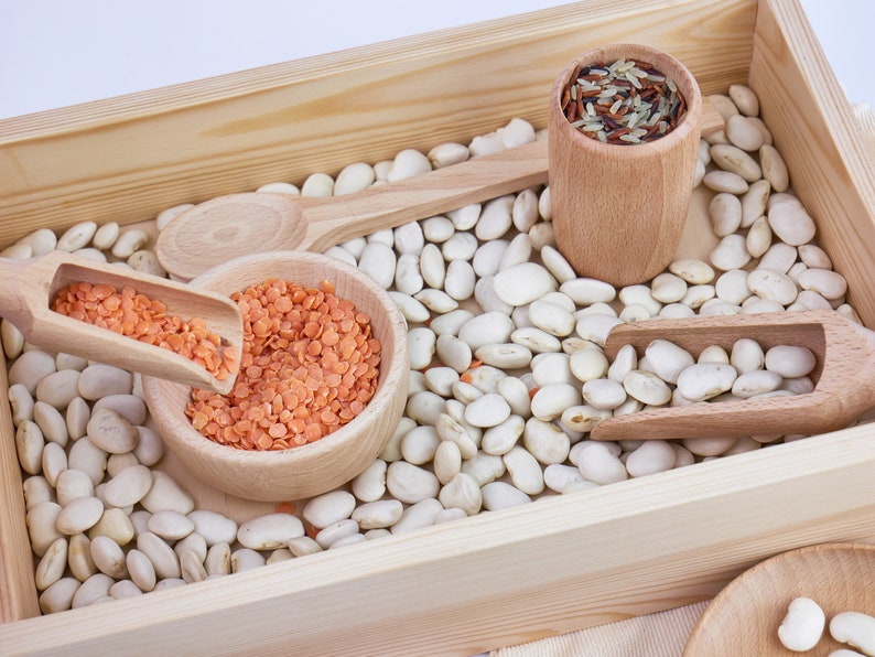 Wooden sensory tray with wooden scoops, cup and bowl inside.