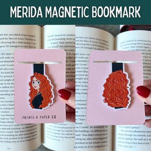 May include: Pink Merida magnetic bookmark with a black and white illustration of Merida from the Disney movie Brave. The bookmark has a black magnetic strip and the text "PRINTS N PAPER CO".