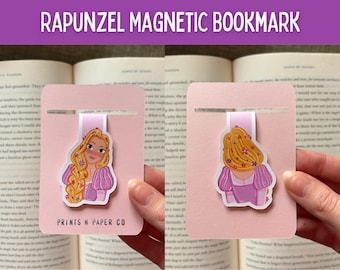 Puede incluir: Un marcapáginas magnético rosa con una ilustración de Rapunzel. El marcapáginas tiene una cinta rosa y un recorte para la página. La ilustración muestra a Rapunzel con pelo largo rubio y un vestido rosa. El texto "RAPUNZEL MAGNETIC BOOKMARK" está en la parte superior.