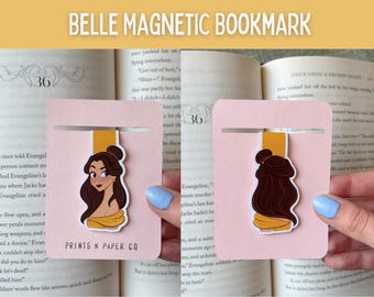 Puede incluir: Marcapáginas magnético rosa con una ilustración de dibujos animados de Bella. El marcapáginas tiene una pestaña amarilla y una tira magnética plateada. El texto "BELLE MAGNETIC BOOKMARK" está en la parte superior.
