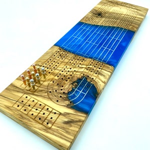 Superbe planche de cribbage en bois d'olivier + résine époxy bleu maui | Chevilles en métal avec espace de rangement inclus | Gravure disponible !