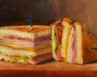 Puede incluir: Dos sándwiches de jamón y queso a la parrilla sobre una superficie de madera. Un sándwich tiene un palillo de dientes azul que sobresale.