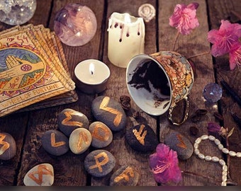 May include: A wooden table with a variety of divination tools, including tarot cards, runes, candles, and a cup of coffee grounds. The table is decorated with pink flowers and a pearl necklace.