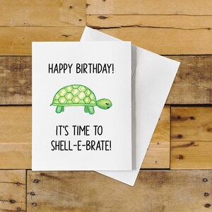 May include: A white card with a green turtle illustration and the text "Happy Birthday! It's time to shell-ebrate!"