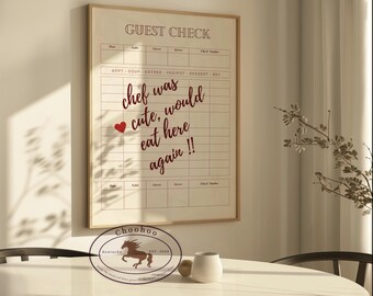 May include: A framed print with a guest check design. The print features the text "GUEST CHECK" and a handwritten message that reads "chef was cute, would eat here again!!". The print is framed in a light wood frame and has a white background.