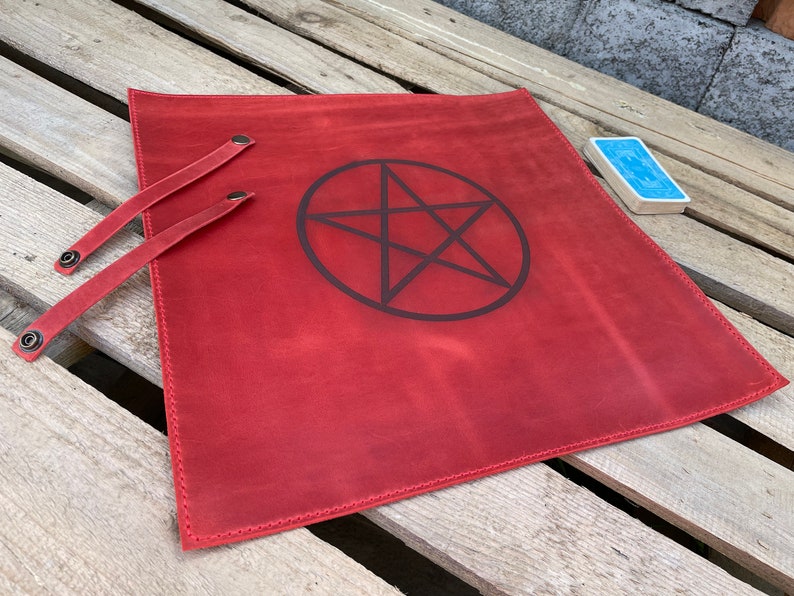 May include: Red leather tarot cloth with a black pentagram design and two leather straps with metal buckles.