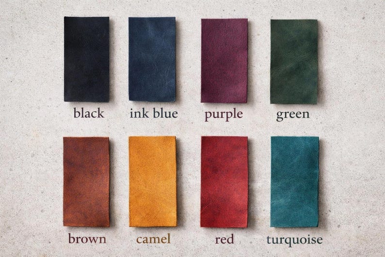 May include: Eight rectangular leather swatches arranged in two rows. Colors include black, ink blue, purple, green, brown, camel, red, and turquoise. Each swatch is labeled with its corresponding color name printed in a serif font below it.