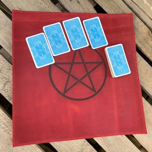 May include: Red leather tarot cloth with a pentagram design and five blue tarot cards placed around it.
