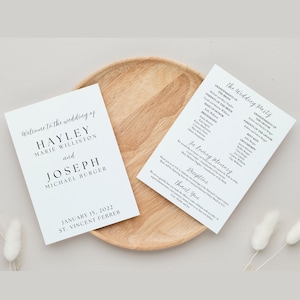 May include: Two white wedding programs with black text on a wooden plate. The left program reads "Welcome to the wedding of Hayley Marie Williston and Joseph Michael Burger" with the date January 15, 2022. The right program lists the wedding party.