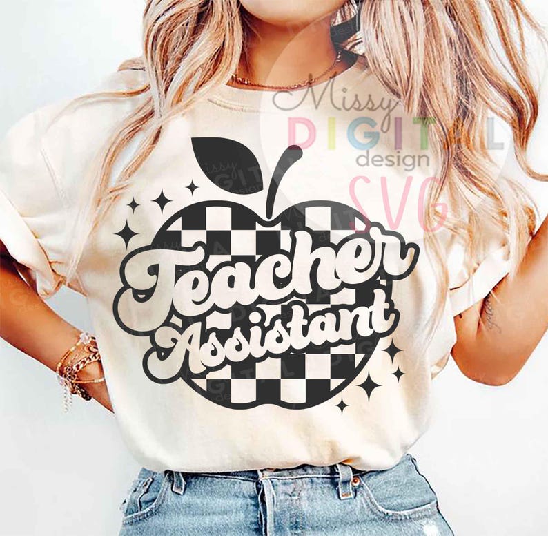 May include: Cream-colored t-shirt featuring a black and white checkered apple design with the words "Teacher Assistant" in a retro font. The design includes black star accents. The shirt is a casual style.