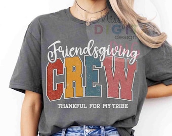 May include: A gray Friendsgiving Crew t-shirt with a colorful design. The word "Friendsgiving" is in white script above the word "CREW" in red, yellow, teal, and red block letters. The text "THANKFUL FOR MY TRIBE" is below.