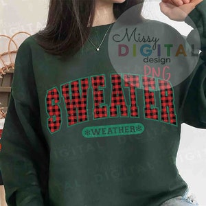 Puede incluir: Sudadera verde oscuro con la frase "SWEATER WEATHER" en un dise&ntilde;o de cuadros rojos y negros. El texto est&aacute; delineado en color turquesa, con un copo de nieve. Prenda de vestir casual y de temporada.