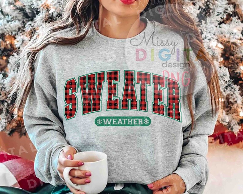 Puede incluir: Una sudadera gris con la frase "SWEATER WEATHER" en un dise&ntilde;o de cuadros rojos y negros con ribetes verdes. La persona sostiene una taza blanca.