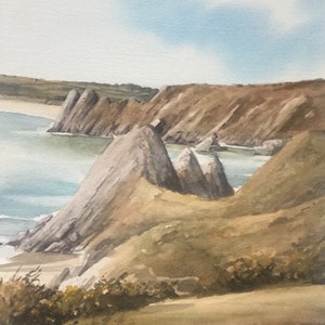 May include: A watercolour painting depicting a rocky coastline with a blue sky and white clouds. The cliffs are brown and grey, and the water is a light blue. The painting is in a realistic style.