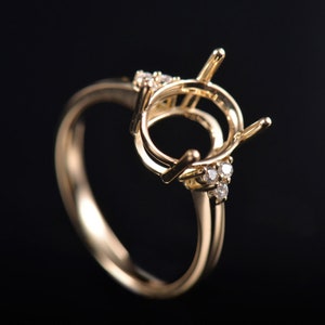 May include: A gold ring with a round setting for a gemstone. The setting is surrounded by small diamonds.