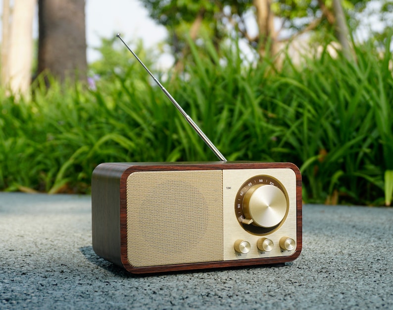 Pu&ograve; includere: Una radio in legno in stile vintage con un quadrante dorato e un'antenna in metallo. La radio ha un quadrante con numeri e una grande manopola per la sintonizzazione. Ci sono tre manopole pi&ugrave; piccole sul davanti della radio.
