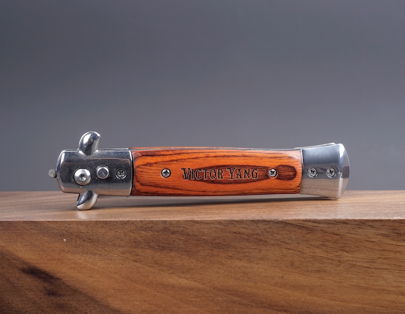 May include: A silver and wood pocket knife with the name "Victor Yang" engraved on the handle.