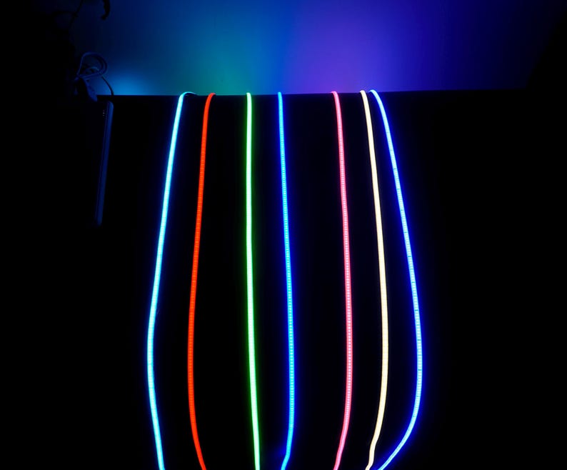 May include: A collection of glowing, flexible LED light strips in various colors, including blue, red, green, and pink, against a black background. The lights are suspended from above, creating a vibrant and colorful display.