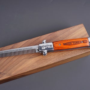 May include: A silver and wood pocket comb with a personalized inscription "VICTOR YANG" on the handle. The comb is engraved with the text "A GREAT HAIRSTYLE IS THE BEST ACCESSORY."