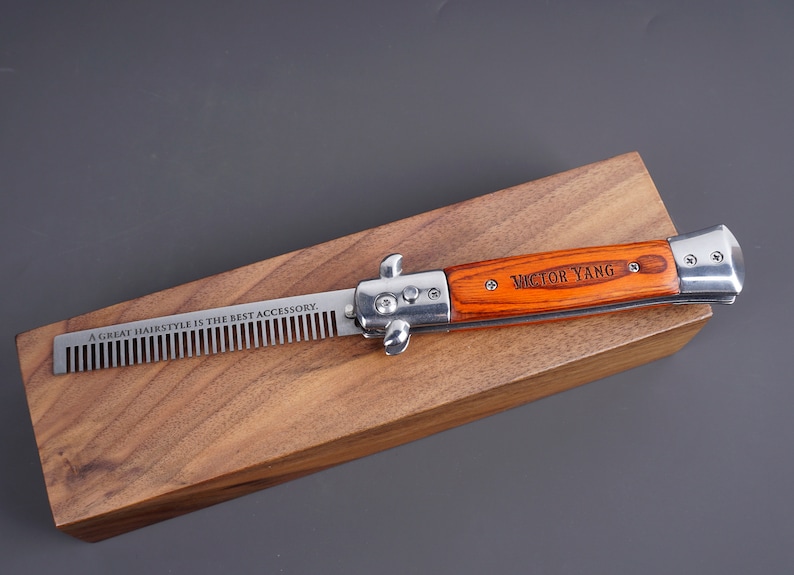 May include: A silver and wood pocket comb with a personalized inscription "VICTOR YANG" on the handle. The comb is engraved with the text "A GREAT HAIRSTYLE IS THE BEST ACCESSORY."