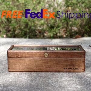May include: A wooden box with a glass top and a brass latch. The box is engraved with the name "Victor Yang".