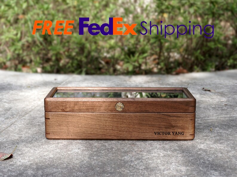 May include: A wooden box with a glass top and a brass latch. The box is engraved with the name "Victor Yang".