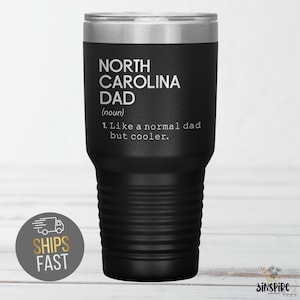 May include: Black insulated tumbler with a silver lid. The tumbler features the text "NORTH CAROLINA DAD (noun) 1. Like a normal dad but cooler." A sticker on the bottom left says "SHIPS FAST".