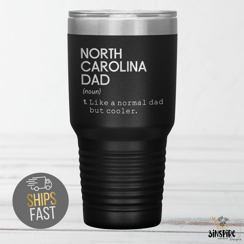 May include: Black insulated tumbler with a silver lid. The tumbler features the text "NORTH CAROLINA DAD (noun) 1. Like a normal dad but cooler." A sticker on the bottom left says "SHIPS FAST".