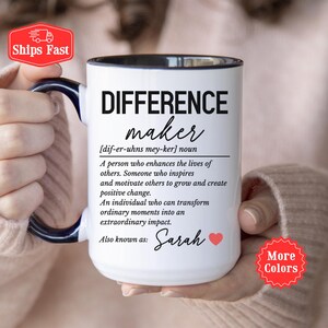Può includere: Tazza in ceramica bianca con interno e manico neri, con la scritta "DIFFERENCE maker" e una definizione. La tazza include anche il nome "Sarah" e un simbolo a forma di cuore. È visibile un adesivo rosso con "Spedizioni veloci".