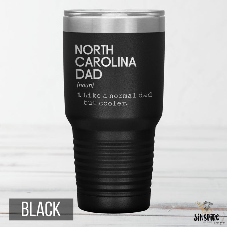 May include: A black insulated tumbler with a silver lid. The tumbler features the text "NORTH CAROLINA DAD (noun) 1. Like a normal dad but cooler." The word "BLACK" is printed at the bottom.