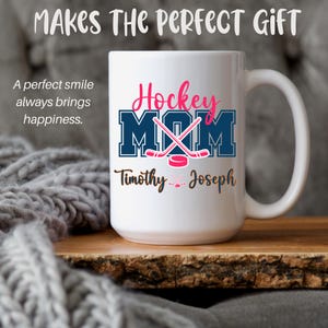 May include: White ceramic mug featuring the text "Hockey Mom" in pink and blue, with hockey sticks and a puck. The names "Timothy" and "Joseph" are printed below. The mug also has the text "Makes the perfect gift" and "A perfect smile always brings happiness."