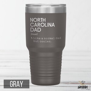 May include: Gray insulated tumbler with a silver lid. The tumbler features the text "NORTH CAROLINA DAD (noun) 1. Like a normal dad but cooler." The word "GRAY" is printed at the bottom of the tumbler.