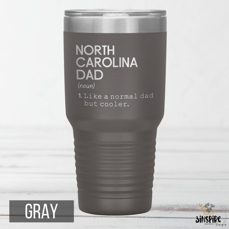 May include: Gray insulated tumbler with a silver lid. The tumbler features the text "NORTH CAROLINA DAD (noun) 1. Like a normal dad but cooler." The word "GRAY" is printed at the bottom of the tumbler.