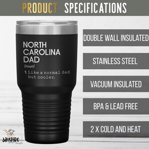 May include: A black insulated tumbler with a silver rim. The tumbler features the text "NORTH CAROLINA DAD (noun) 1. Like a normal dad but cooler." Additional text indicates it is double-wall insulated, stainless steel, vacuum insulated, BPA & lead free, and for cold and heat.