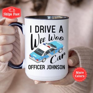 May include: White ceramic mug with a black interior and handle. The mug features the text "I DRIVE A Wee Woo Car OFFICER JOHNSON" with a light blue police car graphic. A red "Ships Fast" sticker is in the upper left corner.