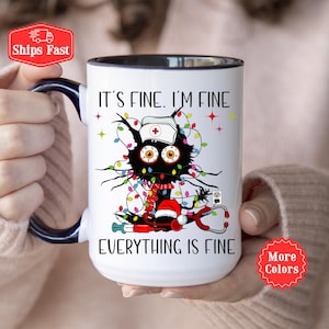 Puede incluir: Taza de cerámica blanca con borde y asa negros. La taza presenta un gato negro con un gorro de Papá Noel rojo y un gorro de enfermera, enredado en luces de Navidad. El texto en la taza dice "It's fine. I'm fine. Everything is fine."