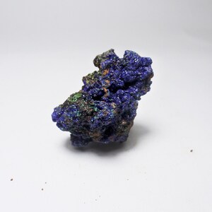 Puede incluir: Un espécimen de mineral de azurita rugoso, de color azul y verde, con una forma natural irregular.