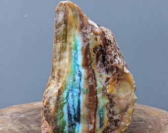 May include: A large, rough, natural stone with a striking blue, green, and brown banded pattern. The stone has a smooth, polished surface and is a beautiful example of natural beauty.