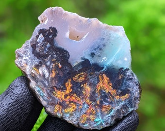 May include: A polished agate slice with a unique pattern of blue, white, and orange colors. The agate has a natural, rough edge and a smooth, polished surface.