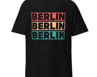 May include: Black t-shirt with the word "BERLIN" stacked three times in a retro design. The top word is in red, the middle in yellow, and the bottom in teal, all on a black background.