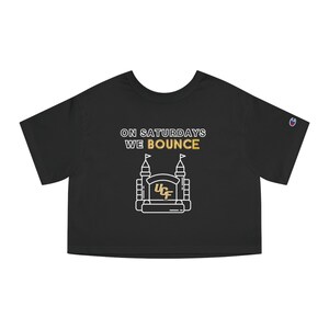 May include: Black cropped t-shirt with white text that reads "On Saturdays We Bounce" and a white outline of a bounce house with the letters "UCF" in gold inside.