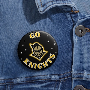 May include: A black button with a gold knight logo and the text "GO KNIGHTS" on a denim jacket.