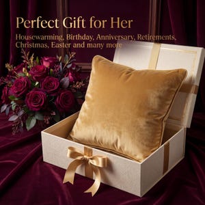 May include: A square gold velvet throw pillow sits inside an open white gift box with a gold ribbon bow. Next to the box is a bouquet of deep red roses. The text reads: Perfect Gift for Her Housewarming, Birthday, Anniversary, Retirements, Christmas, Easter and many more.