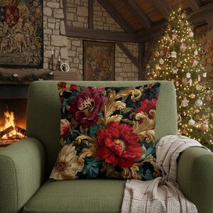 May include: A square throw pillow featuring a dark background with a vibrant floral pattern of large red and cream-colored flowers intertwined with ornate gold-colored acanthus leaf scrolls and deep teal foliage accents throughout the design.