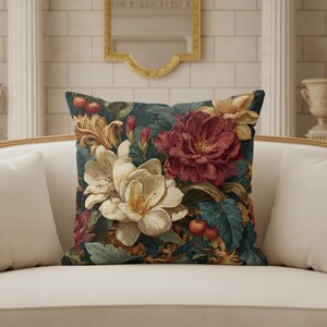 May include: A square throw pillow featuring a dark teal background with a dense botanical print. The design includes large cream-colored flowers, a prominent deep red peony, golden acanthus leaf scrolls, and small red berries with green leaves.